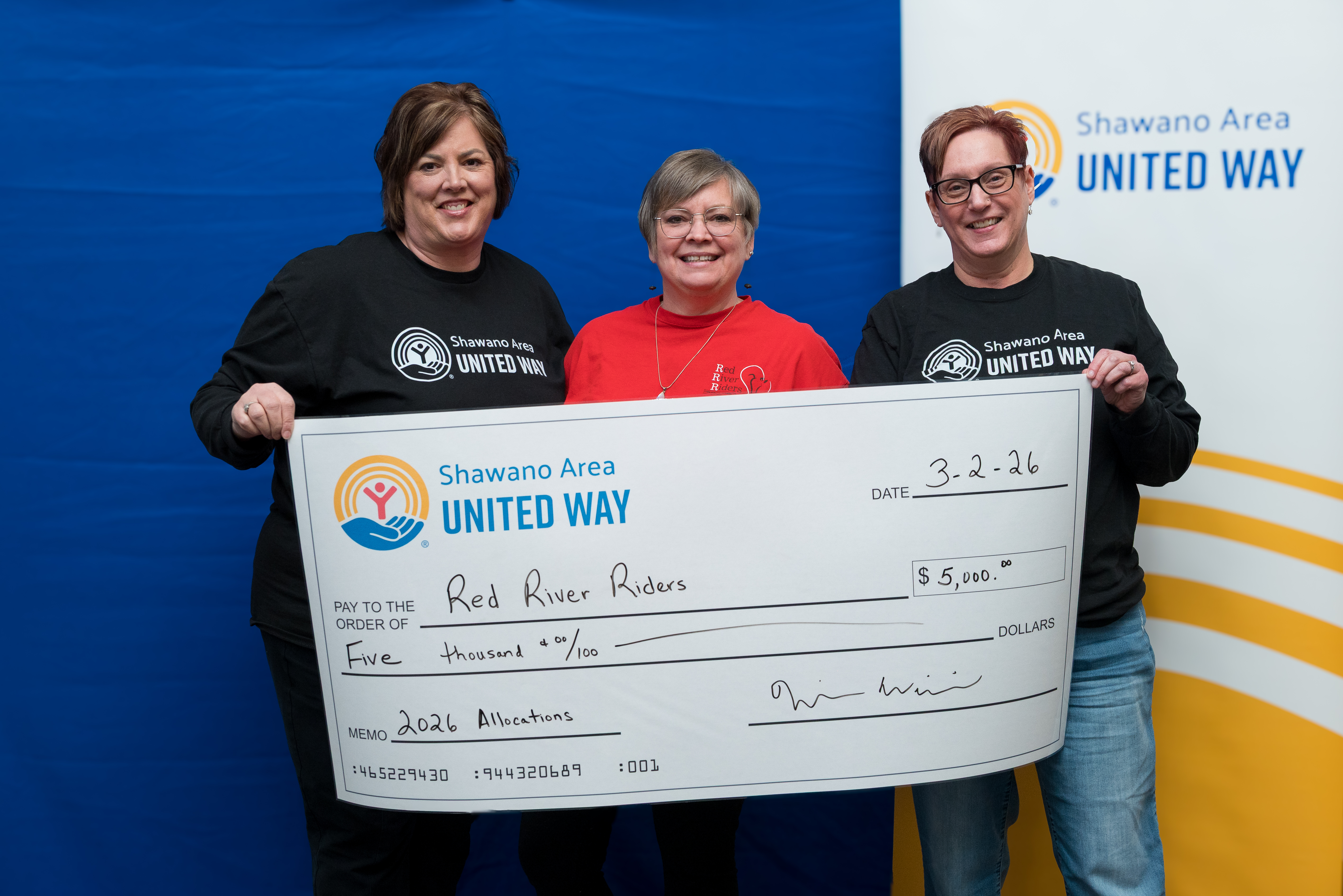 Rhonda Strebel and Carol Sheier from United Way's Board present a check to Jennifer McDermont of Red River Riders